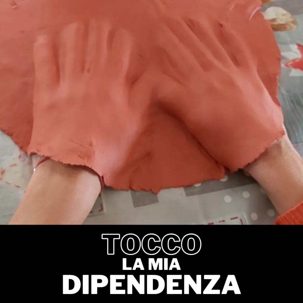 Due mani che lavorano l'argilla arancione e la scritta 'Tocco la mia dipendenza'. Laboratorio di arteterapia.